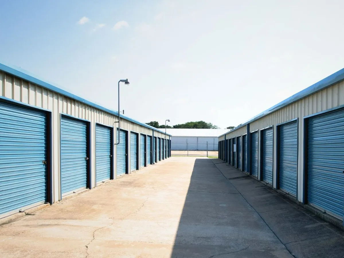 Rows of blue roll-up storage unit doors along a wide drive-up lane